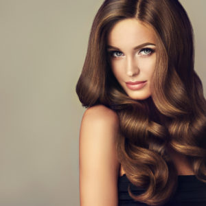 Beautiful model girl with long wavy and shiny hair . Brunette woman with curly hairstyle