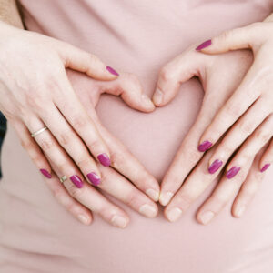 beautiful pregnant  woman with belly in pink dress  and heart