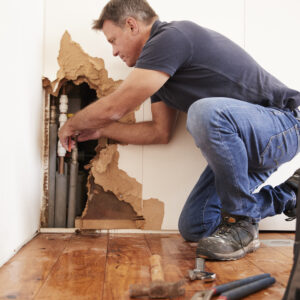 Middle aged man repairing burst water pipe
